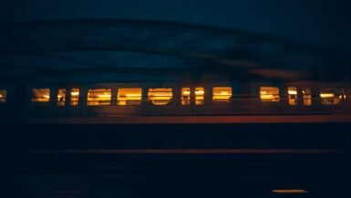 Train de nuit européen filant dans la nuit, fenêtres éclairées