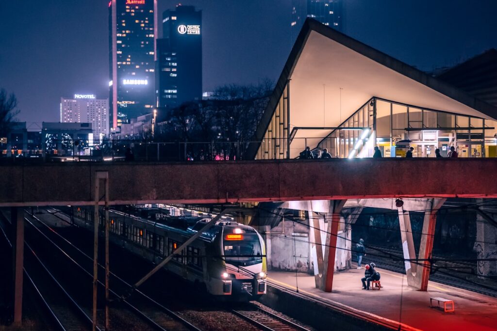 Train arrivant en gare européenne de nuit, éclairage urbain