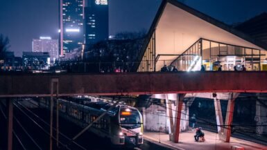 Train arrivant en gare européenne de nuit, éclairage urbain