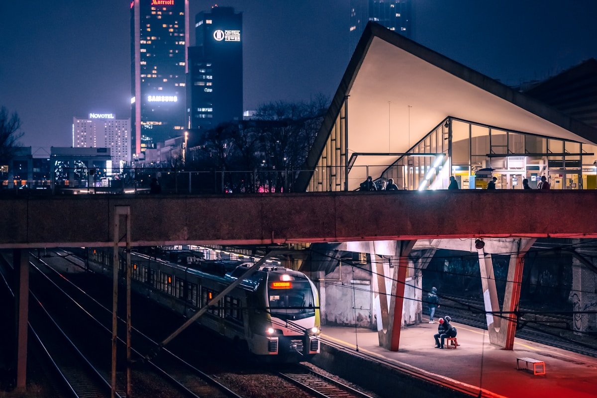 Train arrivant en gare européenne de nuit, éclairage urbain