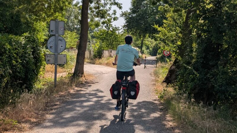 Cycliste avec sacoches sur une petite route ombragée de la Loire à vélo